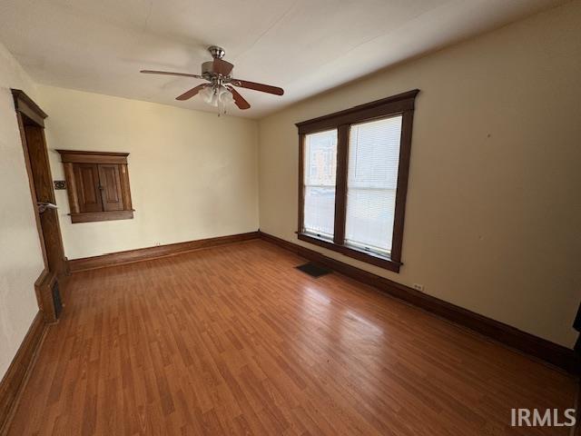 unfurnished room featuring visible vents, a ceiling fan, baseboards, and wood finished floors