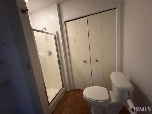 full bathroom with toilet, wood finished floors, and a shower stall