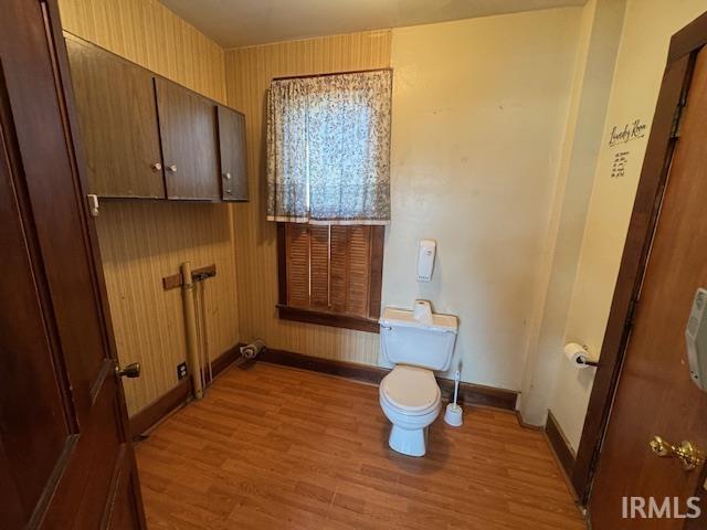 bathroom with toilet, baseboards, and wood finished floors