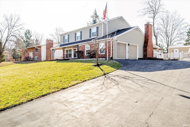 traditional-style home with a front yard, an attached garage, fence, and driveway