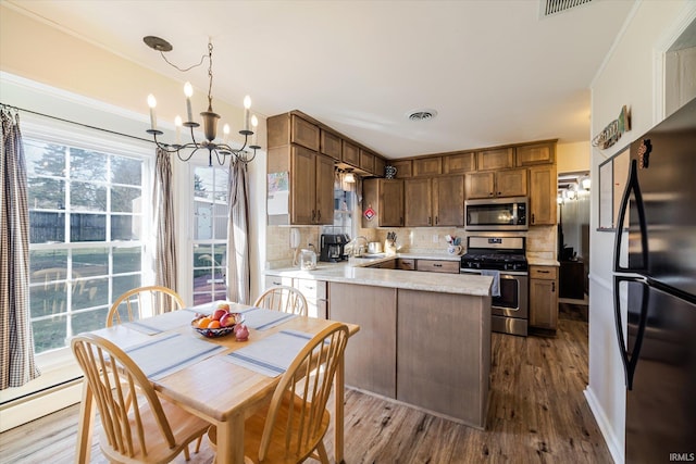 kitchen featuring backsplash, dark wood-style floors, stainless steel appliances, a peninsula, and light countertops