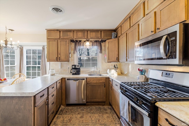 kitchen with visible vents, a peninsula, a sink, stainless steel appliances, and light countertops