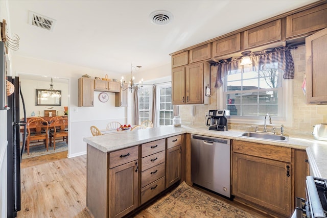 kitchen with visible vents, dishwasher, a peninsula, plenty of natural light, and a sink