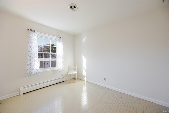 spare room with baseboard heating, baseboards, visible vents, and hardwood / wood-style floors