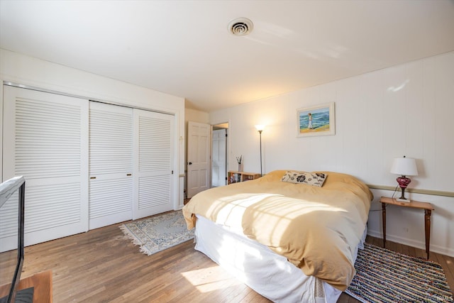 bedroom with visible vents, a closet, and wood finished floors