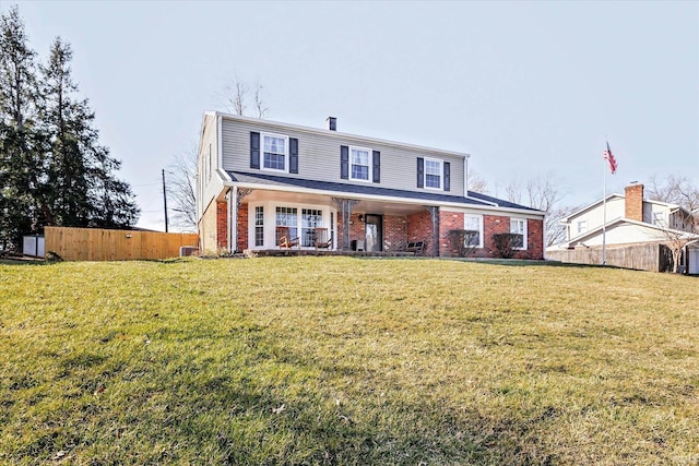 view of front of home with brick siding, cooling unit, a front yard, and fence