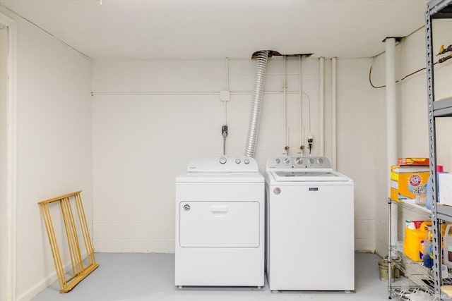 clothes washing area with concrete block wall, separate washer and dryer, and laundry area