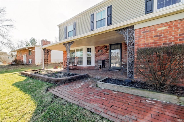 exterior space featuring a patio area, brick siding, and a lawn