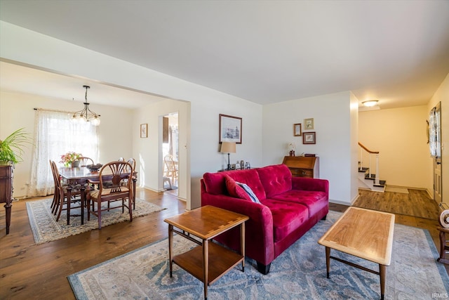 living area featuring a notable chandelier, wood finished floors, and stairs