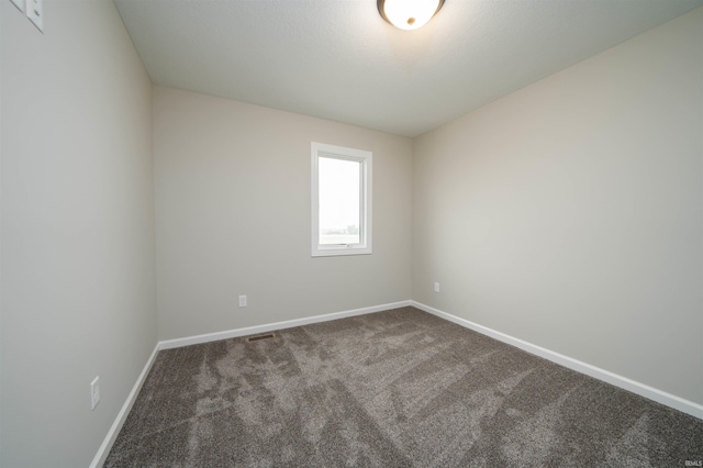 carpeted spare room featuring visible vents and baseboards