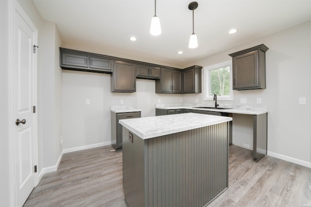 kitchen with a sink, a kitchen island, dark brown cabinets, and light wood-style flooring