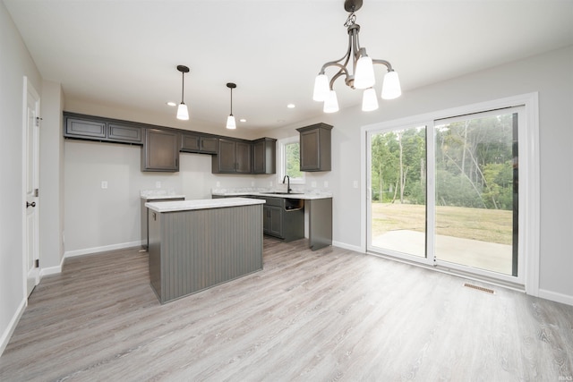 kitchen featuring light wood finished floors, visible vents, a center island, dark brown cabinetry, and a sink