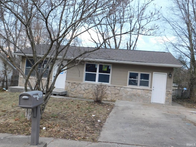 single story home featuring stone siding and roof with shingles