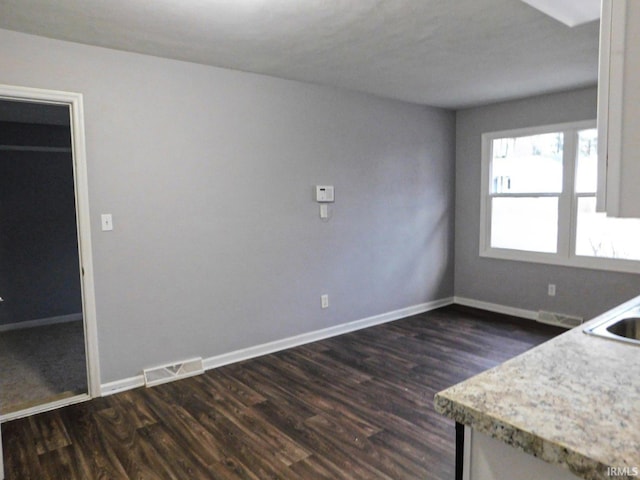 unfurnished dining area with visible vents, dark wood-type flooring, baseboards, and a sink