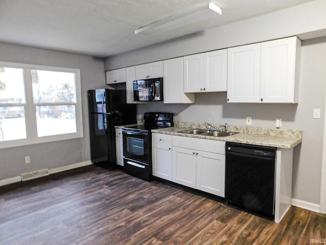 kitchen with baseboards, dark wood-style flooring, a sink, black appliances, and white cabinets