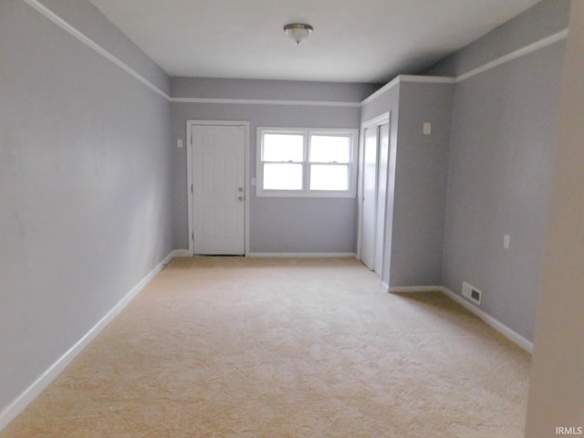 empty room featuring visible vents, baseboards, and light colored carpet