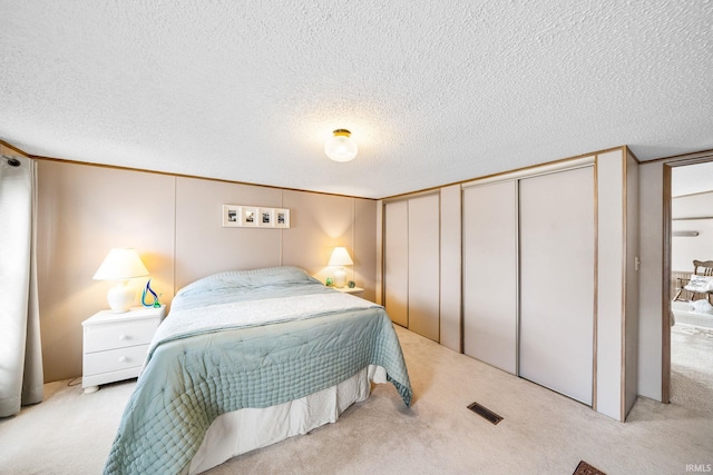 carpeted bedroom featuring visible vents, a closet, and a textured ceiling