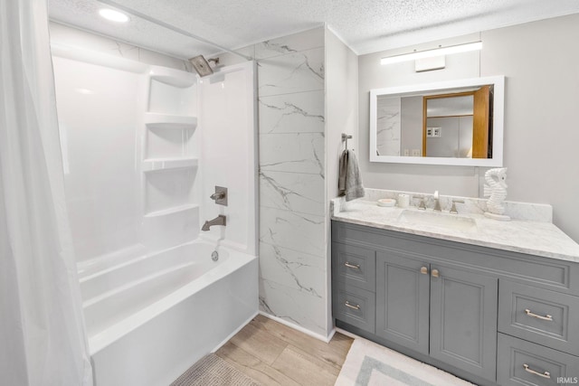 full bathroom featuring shower / washtub combination, vanity, wood finished floors, a textured ceiling, and tile walls