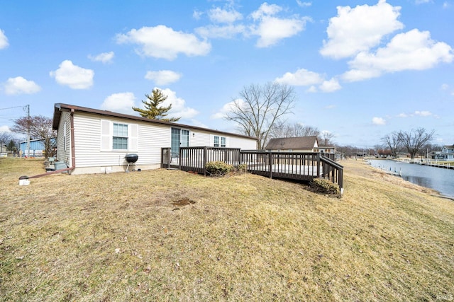 rear view of house with a deck with water view and a yard