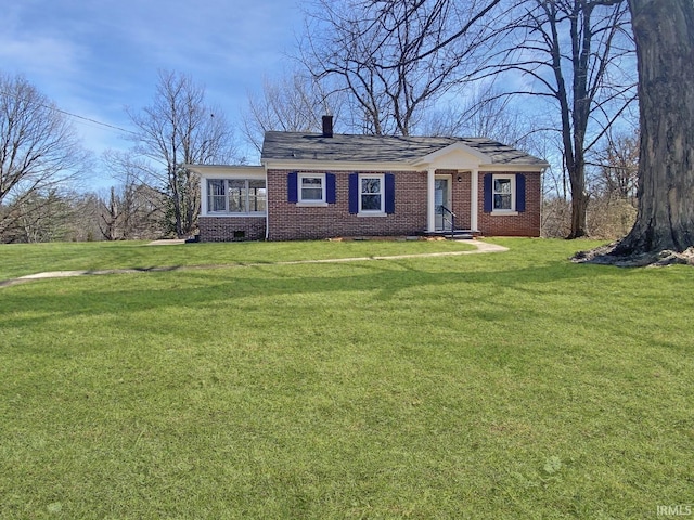 view of front facade with a front yard, a chimney, brick siding, and crawl space