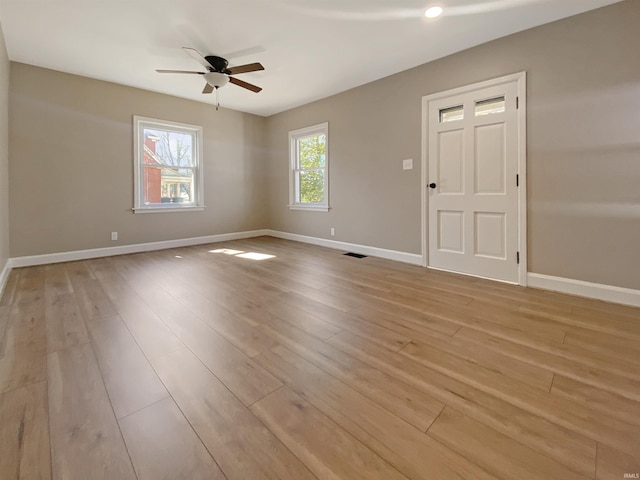 spare room featuring baseboards, light wood finished floors, and ceiling fan