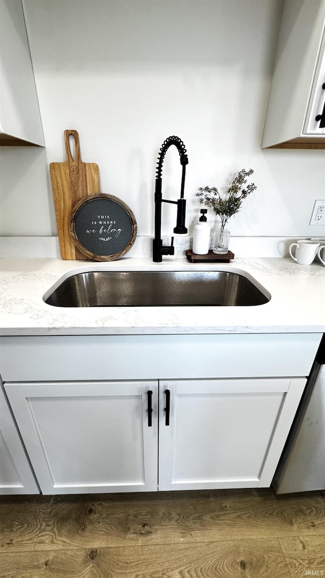 details featuring a sink, light stone countertops, and white cabinetry