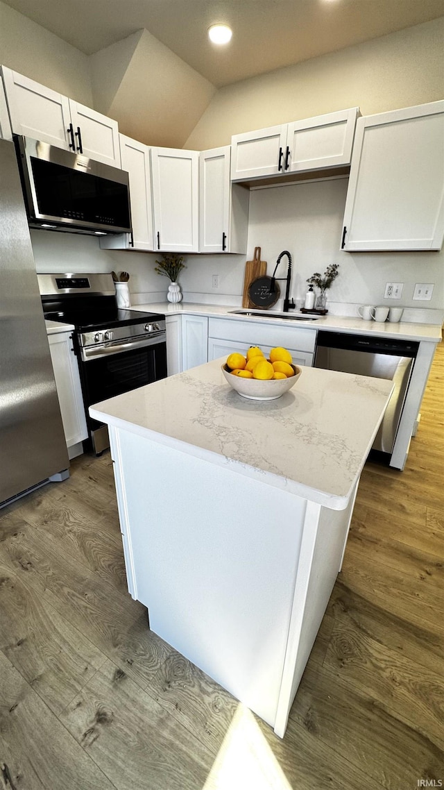 kitchen with a sink, stainless steel appliances, dark wood-style floors, and a center island