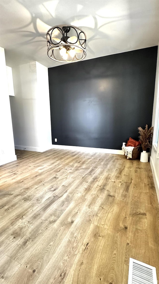 spare room featuring visible vents, baseboards, and wood finished floors