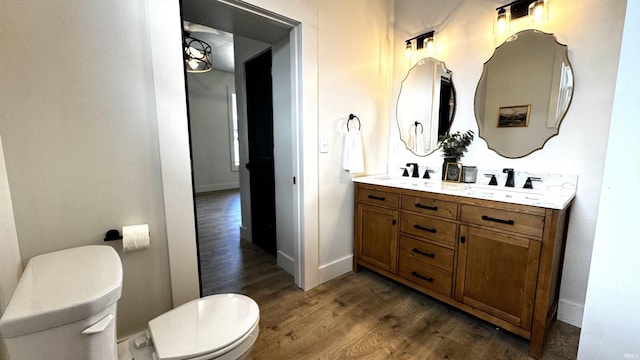 bathroom featuring a sink, toilet, wood finished floors, and double vanity