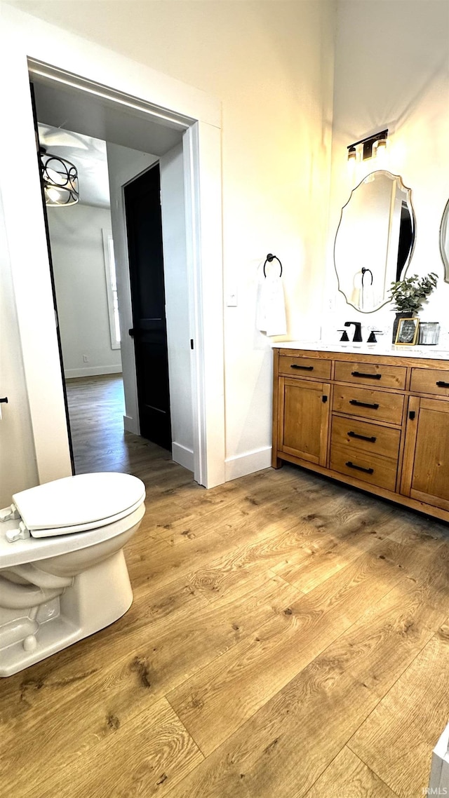 bathroom with vanity, toilet, wood finished floors, and baseboards