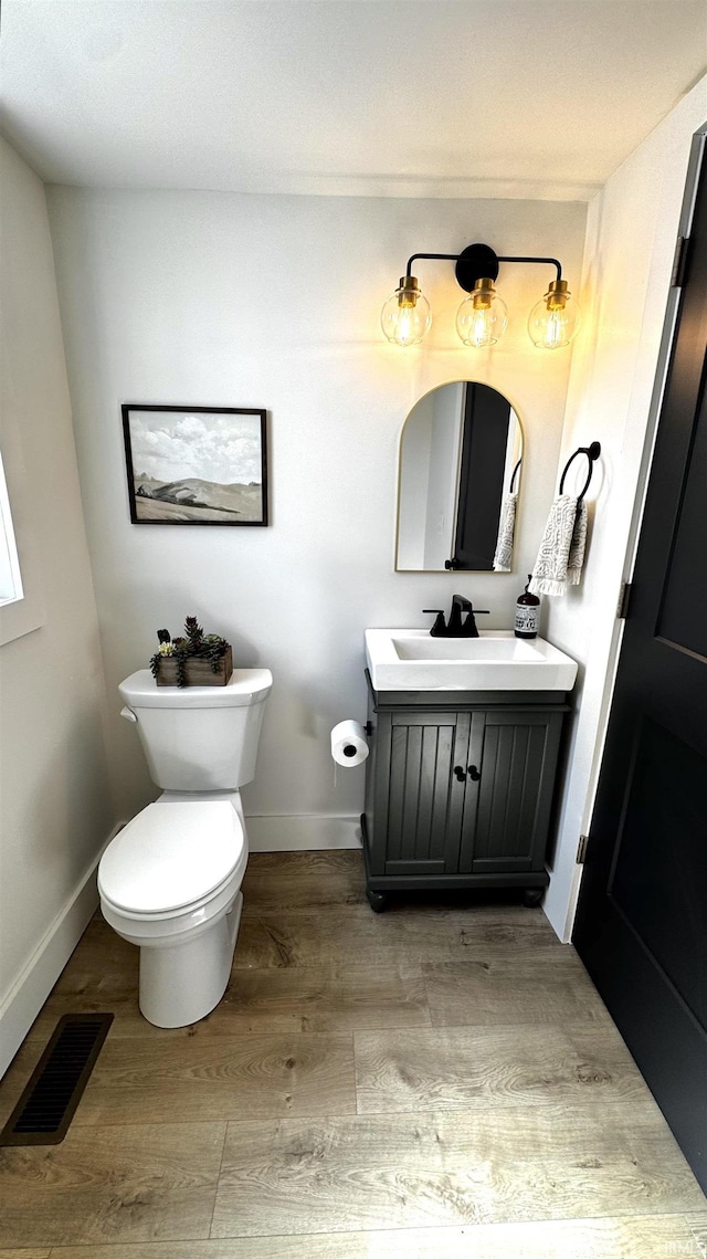 bathroom with visible vents, toilet, wood finished floors, baseboards, and vanity