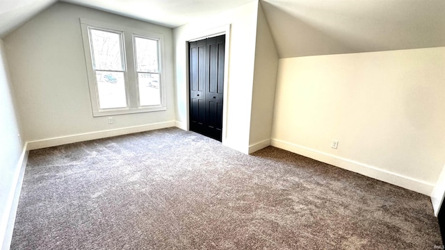 additional living space with dark carpet, baseboards, and vaulted ceiling