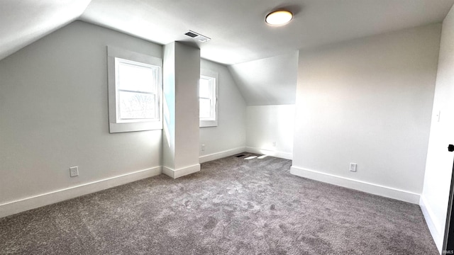 additional living space featuring vaulted ceiling, baseboards, and visible vents