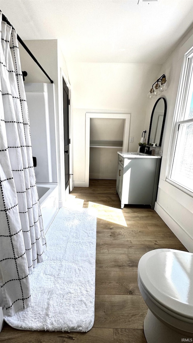 full bathroom with vanity, wood finished floors, shower / bath combo, and baseboards