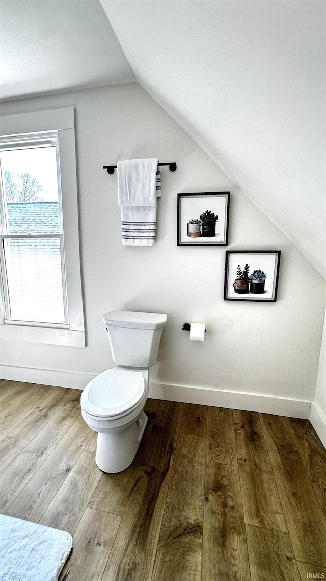 bathroom with toilet, lofted ceiling, baseboards, and wood-type flooring