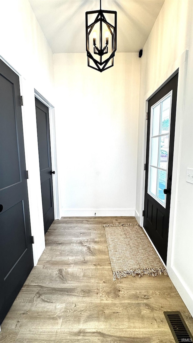 entrance foyer featuring a chandelier, visible vents, baseboards, and wood finished floors