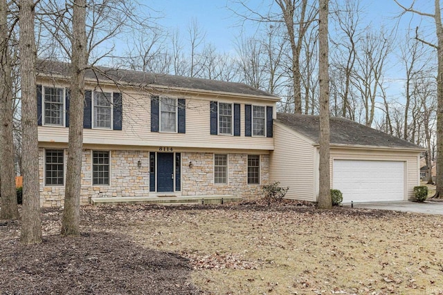 colonial inspired home with stone siding, concrete driveway, and an attached garage