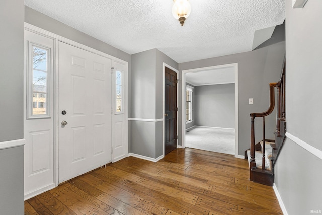 foyer with stairs, a healthy amount of sunlight, baseboards, and wood-type flooring