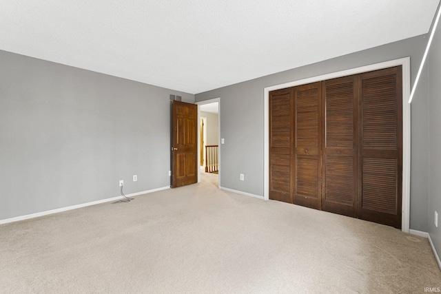 unfurnished bedroom featuring a closet, light colored carpet, and baseboards