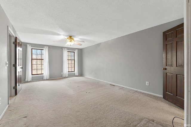 carpeted empty room with baseboards, a textured ceiling, and ceiling fan