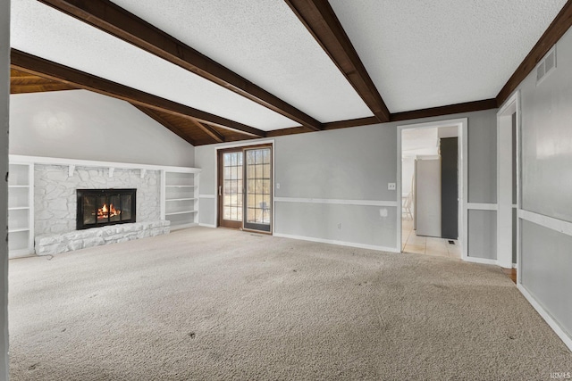 unfurnished living room featuring visible vents, lofted ceiling with beams, a textured ceiling, a fireplace, and light colored carpet