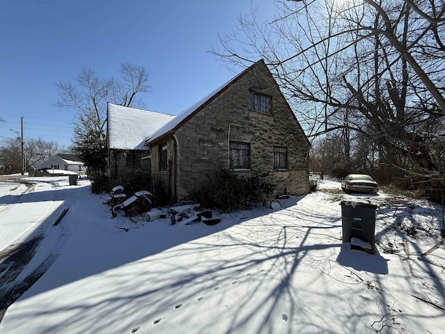 view of snow covered exterior with stone siding