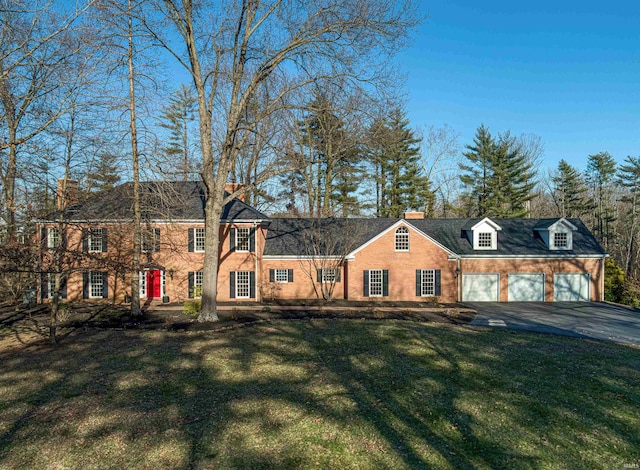 view of front facade with a front lawn, a garage, driveway, and a chimney