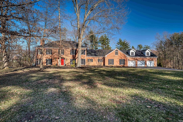 view of front facade with a front yard, brick siding, and a garage