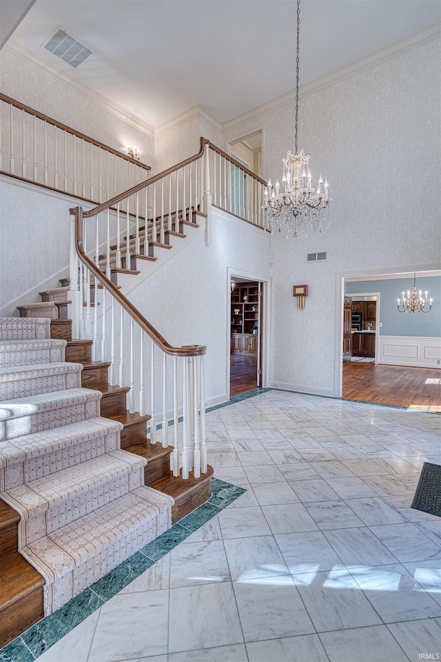 stairs featuring visible vents, a notable chandelier, marble finish floor, and crown molding