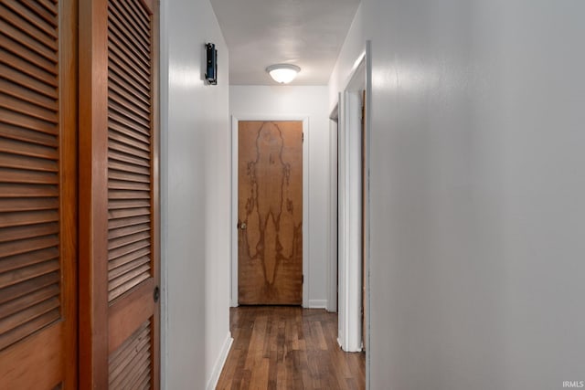 corridor with dark wood finished floors and baseboards