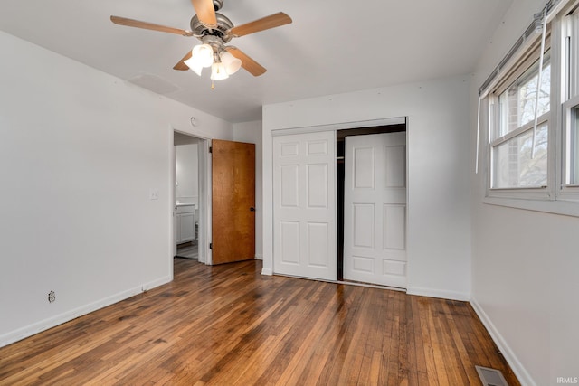 unfurnished bedroom featuring hardwood / wood-style flooring, baseboards, visible vents, and a closet