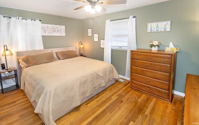 bedroom with light wood finished floors, ceiling fan, and baseboards