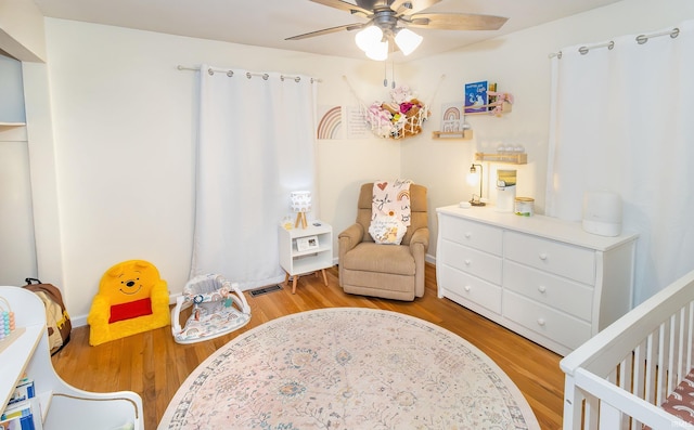 bedroom featuring visible vents, light wood-type flooring, and a nursery area