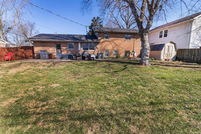 rear view of house with fence, an outdoor structure, a storage unit, a lawn, and brick siding